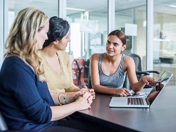 A group of women looking at a laptop.
