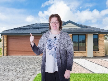 A woman outside her home, giving a thumbs up. 