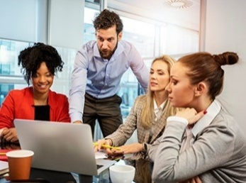 A group of people looking at a laptop together.