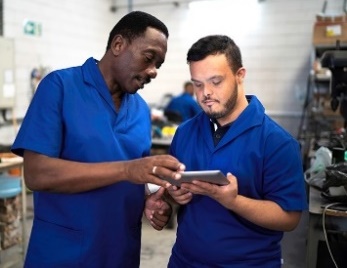 A man showing another man information on an iPad. 