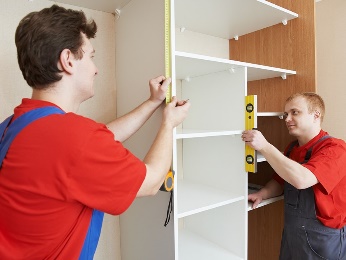Two men assembling a cabinet. 