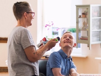 A person helping a man in a wheelchair.