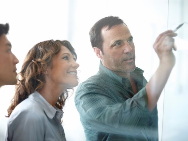 A man showing a woman something he wrote on a board. 