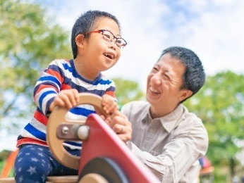 A man and his son playing on a playground.