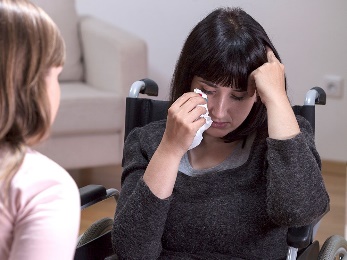 A woman in a wheelchair crying. 