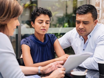 Two women and a man looking at a document together. 