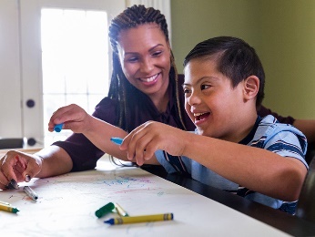 An adult playing with a child with disability.