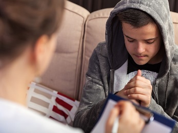 A person talking to a young boy, who is looking sad. 