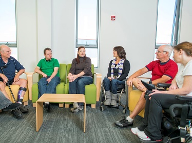 A group of people sitting on couches having a conversation. 