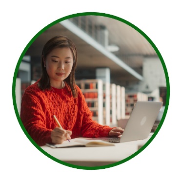 A person using a laptop and writing information.