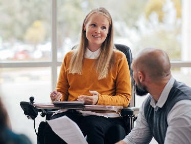 A person in a wheelchair giving a talk to some people.