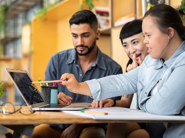 A group of people working on a laptop together. 