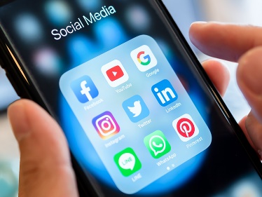 A person with a smartphone and social media apps on the screen.