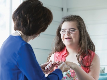 A person holding the hands of someone with disability. 