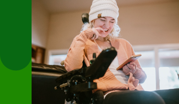 Woman laughing in wheelchair looking at phone