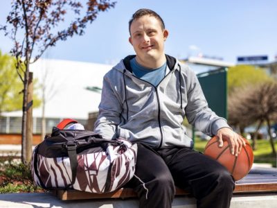 a person sitting on a bench and holding a basketball is smiling at the camera